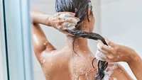 Brunette young woman washing her hair in shower