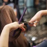 Beautiful hairdresser doing hairstyle to her client in beauty salon