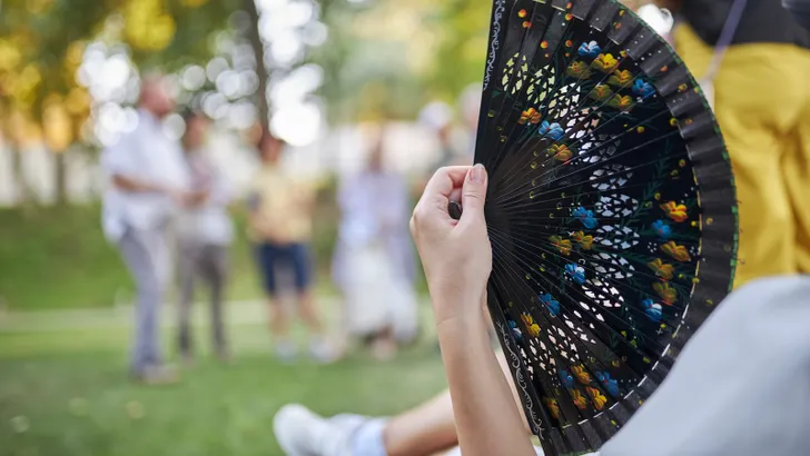 Foto van vrouw met waaier in tuin – Zo overleef je hitte
