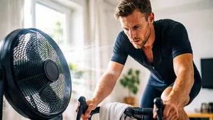 Wielrenner op de fietstrainer met ventilator schuin voor het voorwiel, gericht op borst en gezicht.