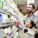 Meisje wijst naar een product op een bovenste plank in de supermarkt.