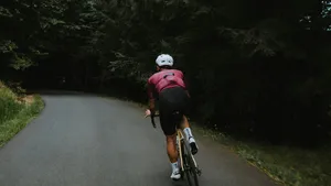Een wielrenner met helm klemt tijdens een afdaling zijn knie tegen de bovenbuis om het klapperen van zijn stuur te stoppen.