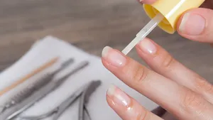 Vrouw brengt nagelolie aan op nagels en nagelriemen, de ontbrekende stap voor gezonde en sterke nagels.
