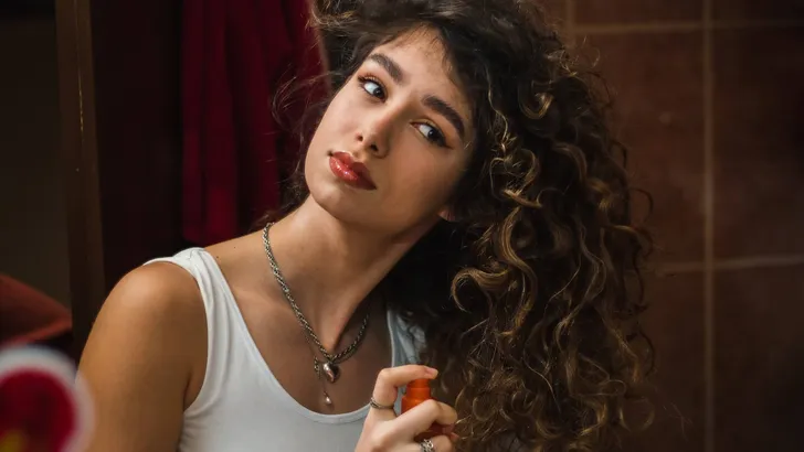 Happy young woman applying hair conditioner.