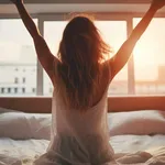 Woman stretching in bed after wake up, back view, entering a day happy and relaxed after good night sleep.