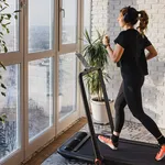 Woman jogging on the modern compact treadmill at home