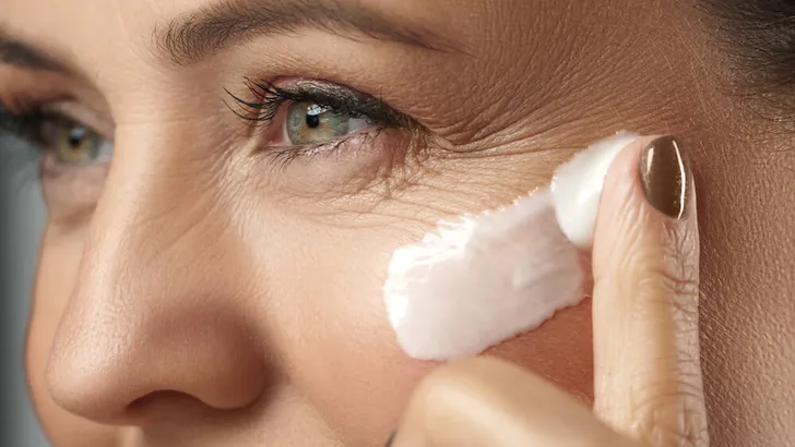 Middle aged woman applying anti-aging cream on her face