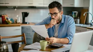 Ter illustratie: bezorgde man kijkt naar zijn rekeningen