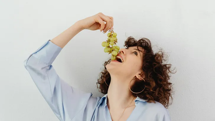 Vrouw eet druiven om huid te beschermen