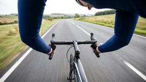 Een wielrenner fietst in een krampachtige, overstrekte houding met stijve armen, reikend naar een te ver gemonteerd stuur.