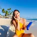 Vrouw smeert zonnebrand op haar gezicht tijdens stranddag.