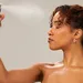 Vrouw die setting spray op haar gezicht spuit - fixing spray