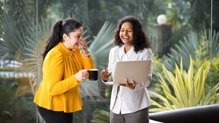 Two happy businesswomen discussing at office