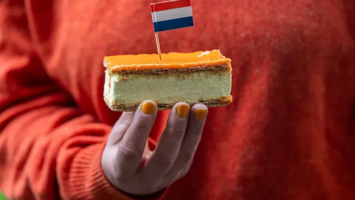 Orange Tompouce in hand, selective focus. A popular pastry eaten in The Netherlands during King's Day celebrations