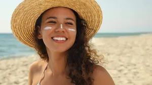 Beautiful African American woman with sun protection cream on fa