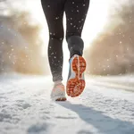 Back view of woman's legs with sport shoes jogging in snow