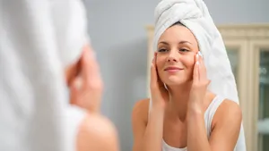 Vrouw doet 's ochtends haar skincare terwijl ze in de spiegel kijkt in de badkamer