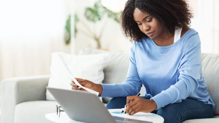 Woman signing papers working on laptop at home