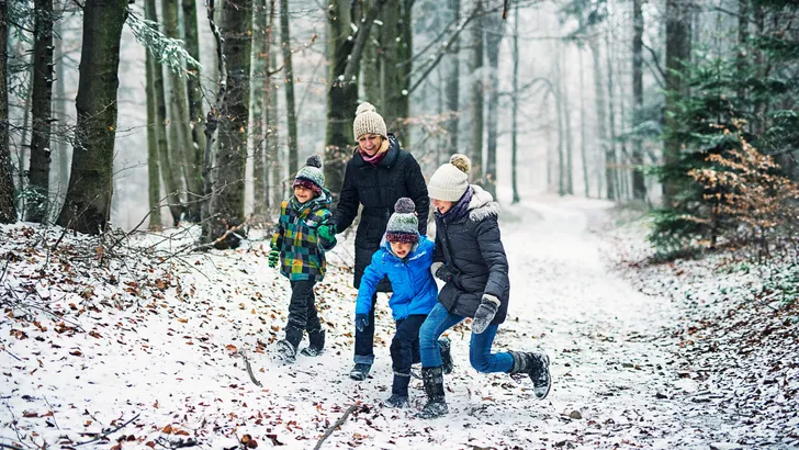 Mother with kids walking in beautiful winter forest