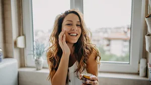 Young woman applies facial cream