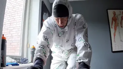 Wielrenner Rick Ottema doet aan gecontroleerde hittetraining op een fietstrainer in een wit schilderspak.