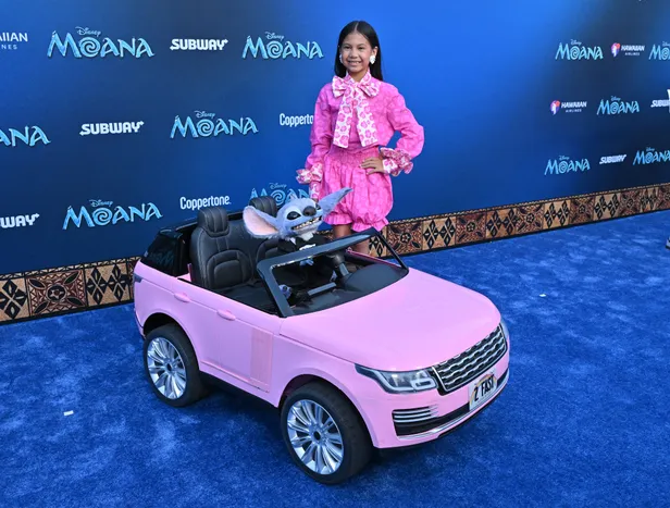 Maia Kealoha in een roze playsuit samen met Stitch (in een roze auto) tijdens de première van de live-action van Moana.