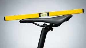 Zijaanzicht van een fietszadel dat te ver naar voren gekanteld is, aangetoond door een waterpas die er horizontaal bovenop ligt.
