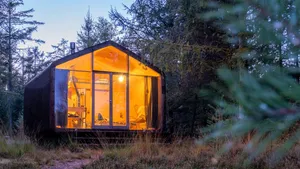 Wooden hut in autumn forest in the Netherlands, cabin off grid ,wooden cabin circled by colorful yellow and red fall trees