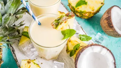 Piña Colada met kokosnoten en ananas op een turqouise tafel