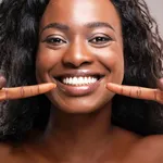 Happy black woman pointing at her perfect white teeth