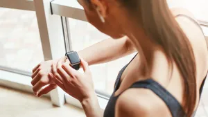 What time is it? Cropped photo of young woman in sportswear checking the time on her sport bracelet while standing in front of window at gym
