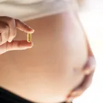 Happy pregnant woman showing medicine