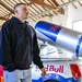 Remco Evenepoel in casual zwarte hoodie poseert naast een zilveren Red Bull Mini Cooper promotiewagen met een gigantisch blik energiedrank op het dak.