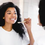 Beautiful young african-american woman brushing her teeth in the bathroom.