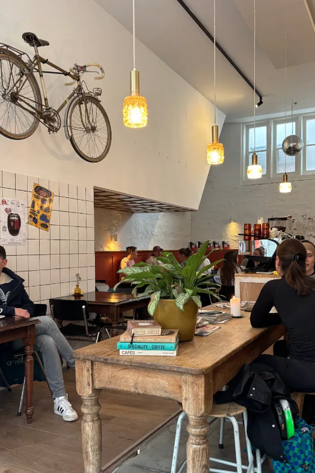 Interieur met lampen en fiets aan de wand van koffiebar.