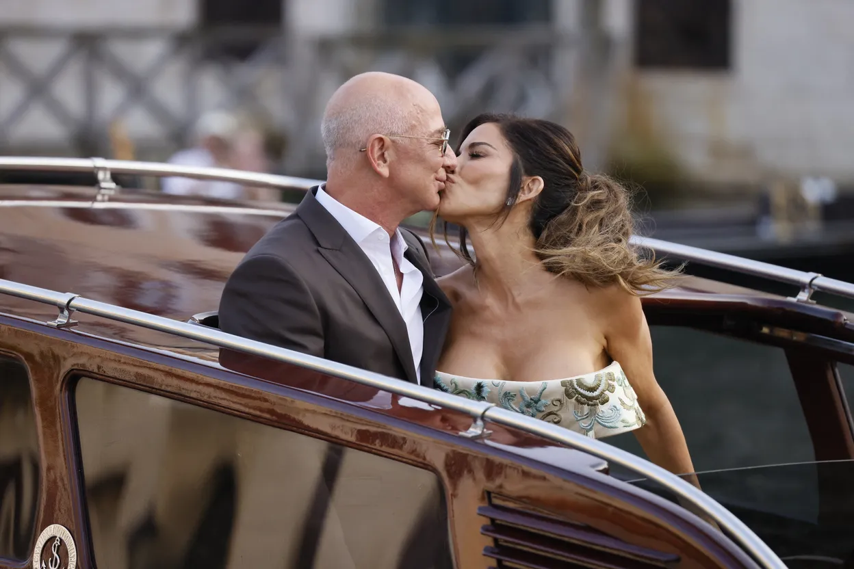 Jeff Bezos en Lauren Sánchez tijdens hun bruiloft kussend in een open auto. 