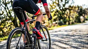 Close-up van een rood schoenplaatje onder een racefietsschoen die is ingeklikt in het pedaal, de vaak over het hoofd geziene oorzaak van pijn aan de binnenkant van het bovenbeen tijdens het fietsen.