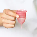 Girl holds a cute menstrual cup in her hand