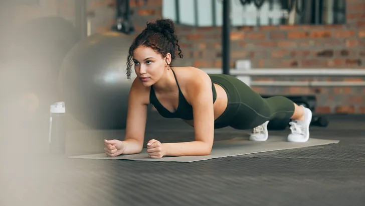 Fitness, gym and workout of a woman doing plank exercise or training for wellness with focus for healthy lifestyle. Female athlete with body weight routine for strong core, sports health and balance