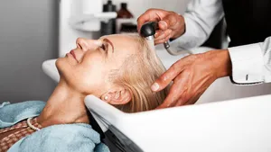 Hair stylist washing mature woman hair