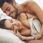 Happy couple having fun on bed under blanket - Young romantic lovers intimate moments - Intimacy and love relationship concept