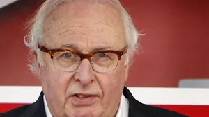 Close-up van Mart Smeets, tegen een rood-witte achtergrond