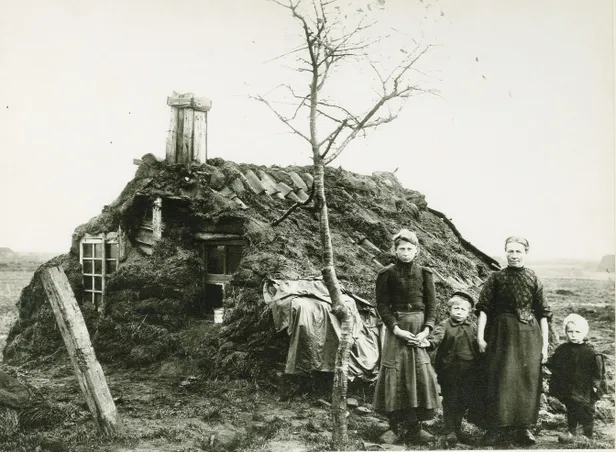 Hinderkien van der Sluis-Nijhof met haar kinderen Egbertien, Evert en Abel voor hun plaggenhut in Westerwolde, 1913