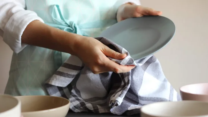 Housewife wipes the dishes with a towel.