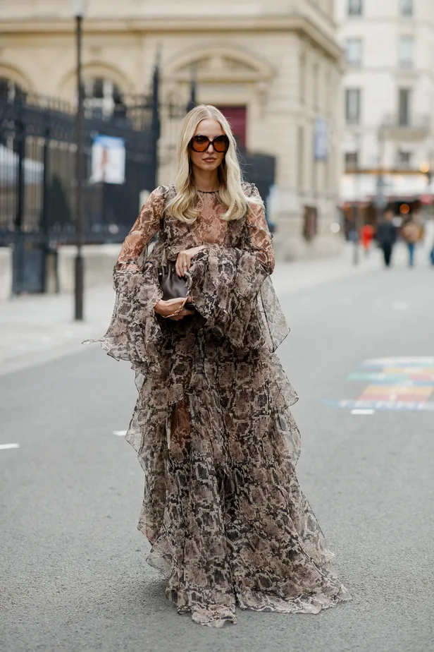 Vrouw in wijde slangenprintjurk tijdens fashion week 