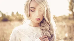 Haircare voor de herfst – Foto van vrouw in gebreide trui met gevlochten blond haar.