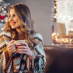 Portrait of woman in front of Christmas tree, drinking hot drink