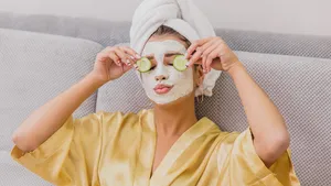 A beautiful young woman gets a face mask in the spa center, lying with cucumbers in her eyes. Happy and gets a lot of fun.