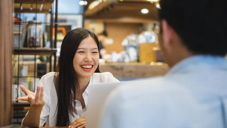 Young beautiful asian business woman in cafe, discussing business during interview with young business man