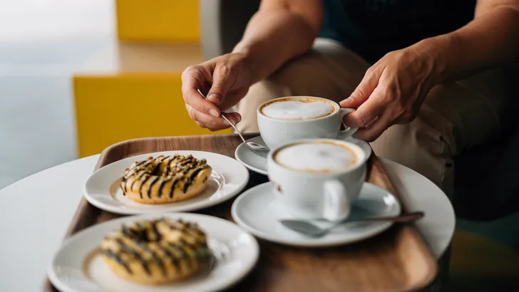 Klok die 16:00 uur aangeeft met een stuk chocolade, illustratie van de bekende middagdip en trek in zoet.
